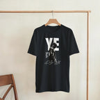 YE Portrait Kanye West Tee, Black Gildan 5000 T-shirt, front graphic print displayed on a wooden hanger